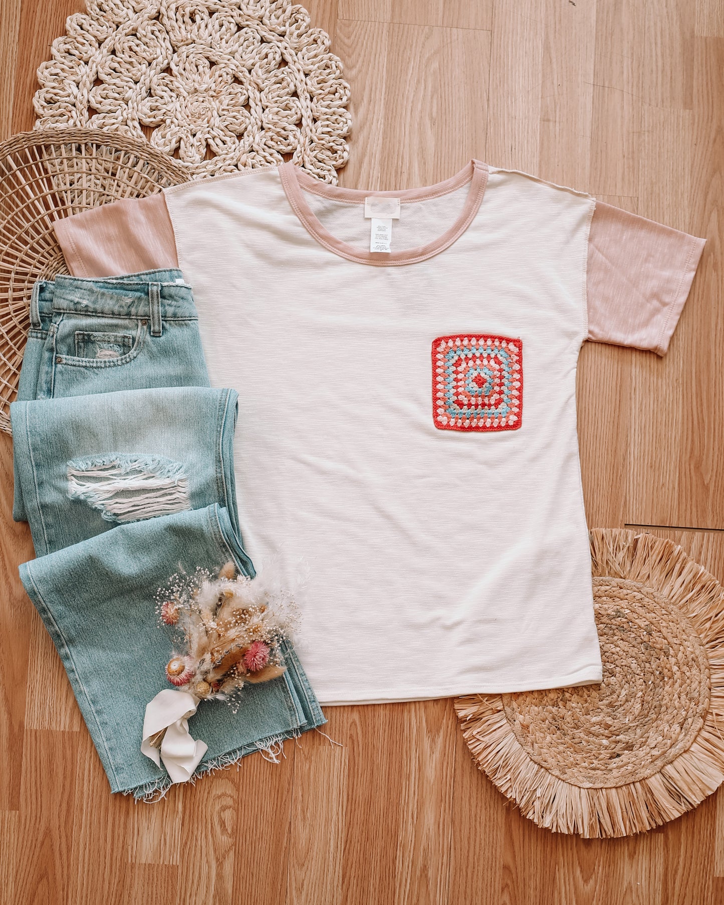 Boho style crochet pocket tee with colorblock pattern flatlay with light wash mom jeans 