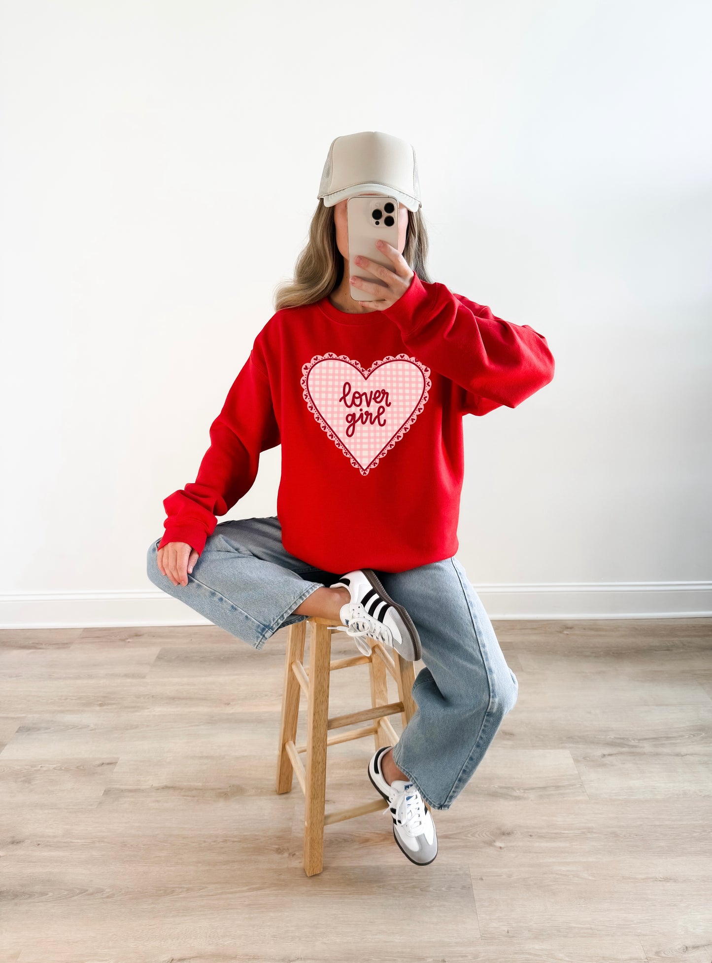 Woman wearing a red Valentine’s Day crewneck sweatshirt with a pink gingham heart and “lover girl” design, casual girly outfit